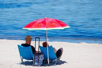 Bañistas sentados bajo una sombrilla en una playa de Kühlungsborn, Alemania