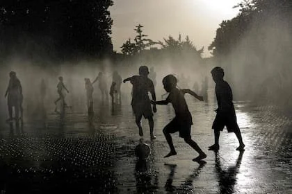 Unos chicos juegan al fútbol bajo una fuente en Madrid, sometida como toda Europa a una ola de calor