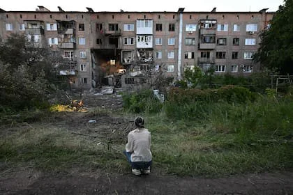 Una chica se sienta frente a un edificio gravemente dañado tras un reciente ataque en la ciudad de Gorlivka, bajo control ruso