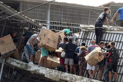 Captura de pantalla que muestra a personas haciendo saqueos en un establecimiento comercial este jueves, en la localidad de Catia La Mar, en el estado costero de La Guaira
