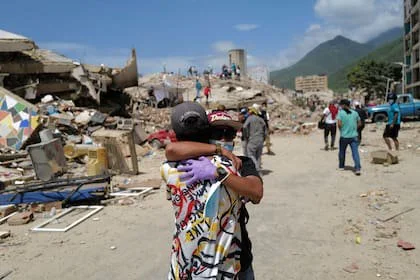 Dos voluntarios se abrazan en medio de la más absoluta desolación en Caraballeda, en el estado de La Guaira