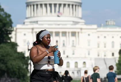 Una persona bebe de un recipiente cerca del Capitolio de los Estados Unidos, en el National Mall de Washington D. C., mientras una intensa ola de calor afecta a la región