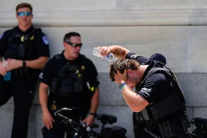 Un policía del Capitolio de Estados Unidos vierte agua en su cabeza, el miércoles 25 de junio de 2025 fuera del Capitolio, en Washington