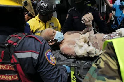 Equipos de rescate trasladan a una persona tras haber sido sacada con vida de los escombros de un edificio colapsado en Caraballeda, estado de La Guaira