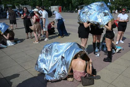 Personas utilizan mantas de emergencia para protegerse del calor mientras llegan al estadio olímpico para un concierto, el 28 de junio de 2026, en Berlín