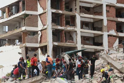 Personas junto a los escombros de un edificio