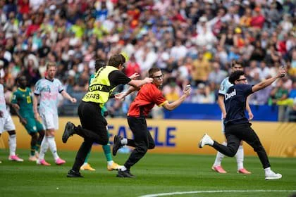 Personal de seguridad persigue a dos de los invasores en el estadio de Seattle ante la mirada de los futbolistas