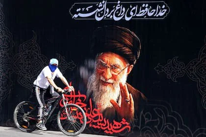 Un hombre anda en bicicleta junto a un cartel con el retrato del líder supremo asesinado de Irán, Ali Khamenei, antes de su funeral en Teherán, el 3 de julio de 2026