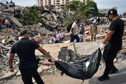 Miembros del Cuerpo de Investigaciones Científicas, Penales y Criminales (CICPC) transportan el cuerpo de un niño recuperado de entre los escombros de un edificio derrumbado en Caraballeda, estado de La Guaira
