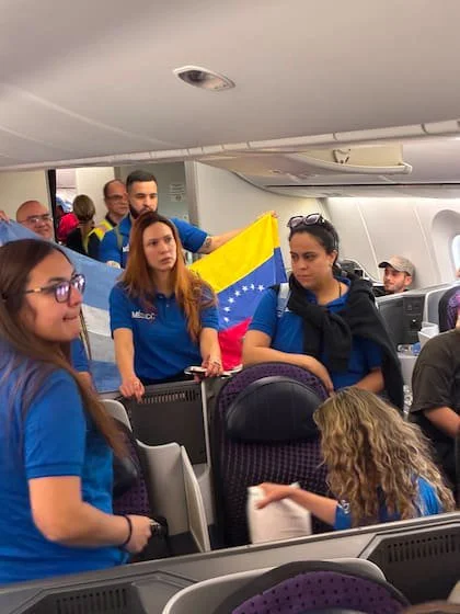 Una brigada de médicos venezolanos residentes en Argentina despliega una bandera de Venezuela junto a una bandera de Argentina en la cabina del avión