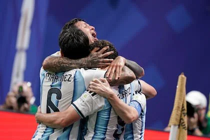 Leandro Paredes y Lisandro Martínez abrazan a Lionel Messi tras el gol del 2-2 parcial