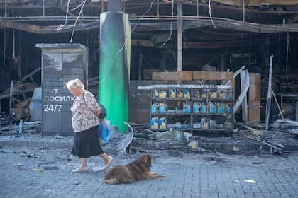 Una mujer pasa junto a un perro cerca de una estación de servicio dañada tras un ataque aéreo ruso en Kamianske, en la región de Dnipropetrovsk, Ucrania, el 7 de julio de 2026